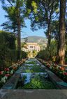Blick zwischen Bäumen und abgestuften Teichen zur mittig im Hintergrund gelegenen Villa Ephrussi de Rothschild